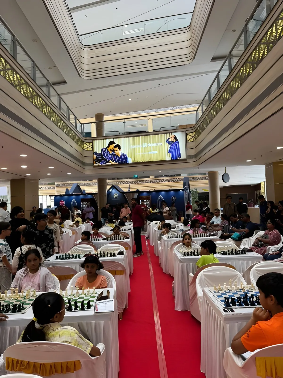 Rows of players deep in their games along the red carpet at the Prime Engage Jr. Chess Championship