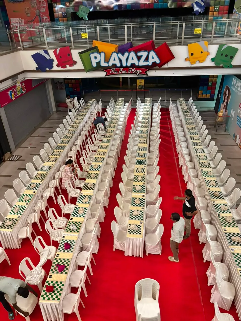 Boards in long rows along a red carpet in the atrium of Centre Square Mall, Kochi, seen from the balcony