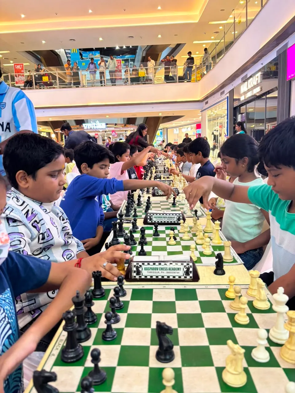 Young players moving pieces during a game at the Kochi qualifier