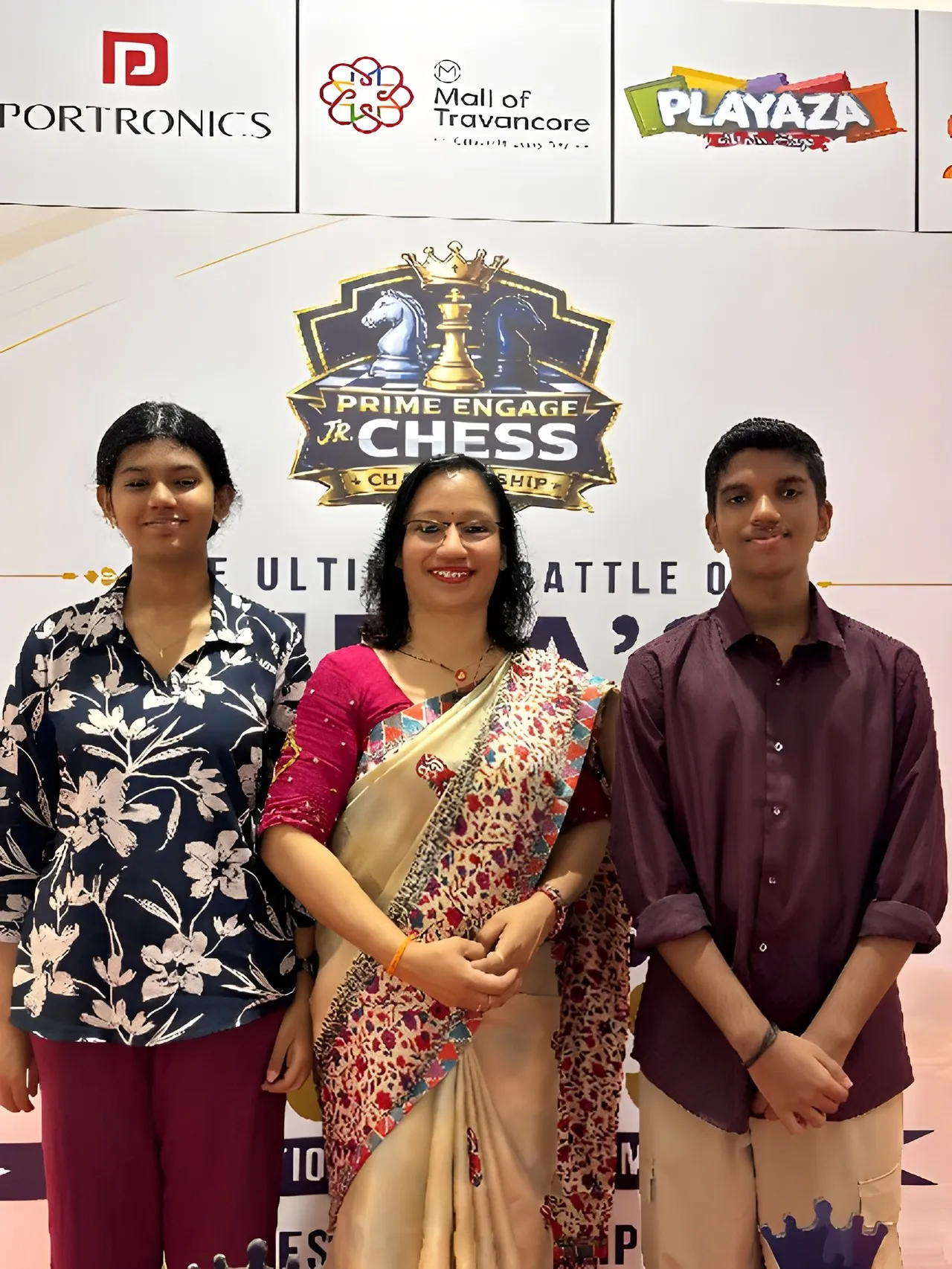 Ms. Subha Rakesh with our chief guests, IM Goutham Krishna and WCM Anupam Sreekumar, at the championship backdrop at the Prime Engage Jr. Chess Championship